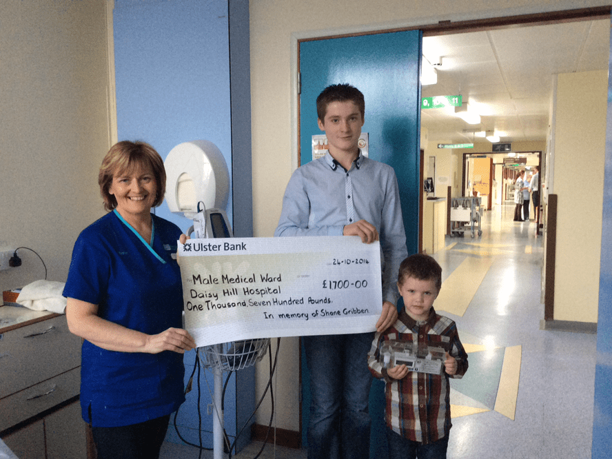 Pictured presenting their cheque to purchase a Vital Signs Monitor and Syringe Driver to Sister Siobhan Rooney, Male Medical Ward at Daisy Hill Hospital in memory of Shane Gribben are his nephews Niall McConville and Daniel Gribben.