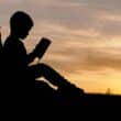 Silhouette of young boy reading a book